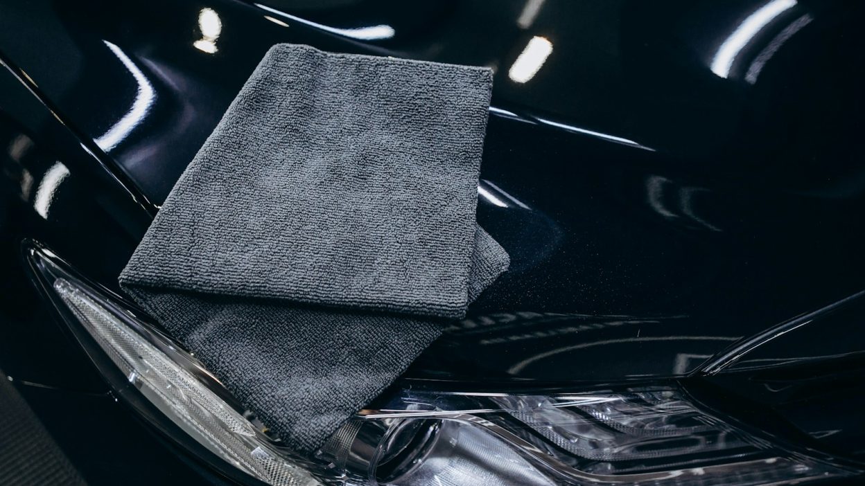 Gray microfiber cloth on a black car hood.